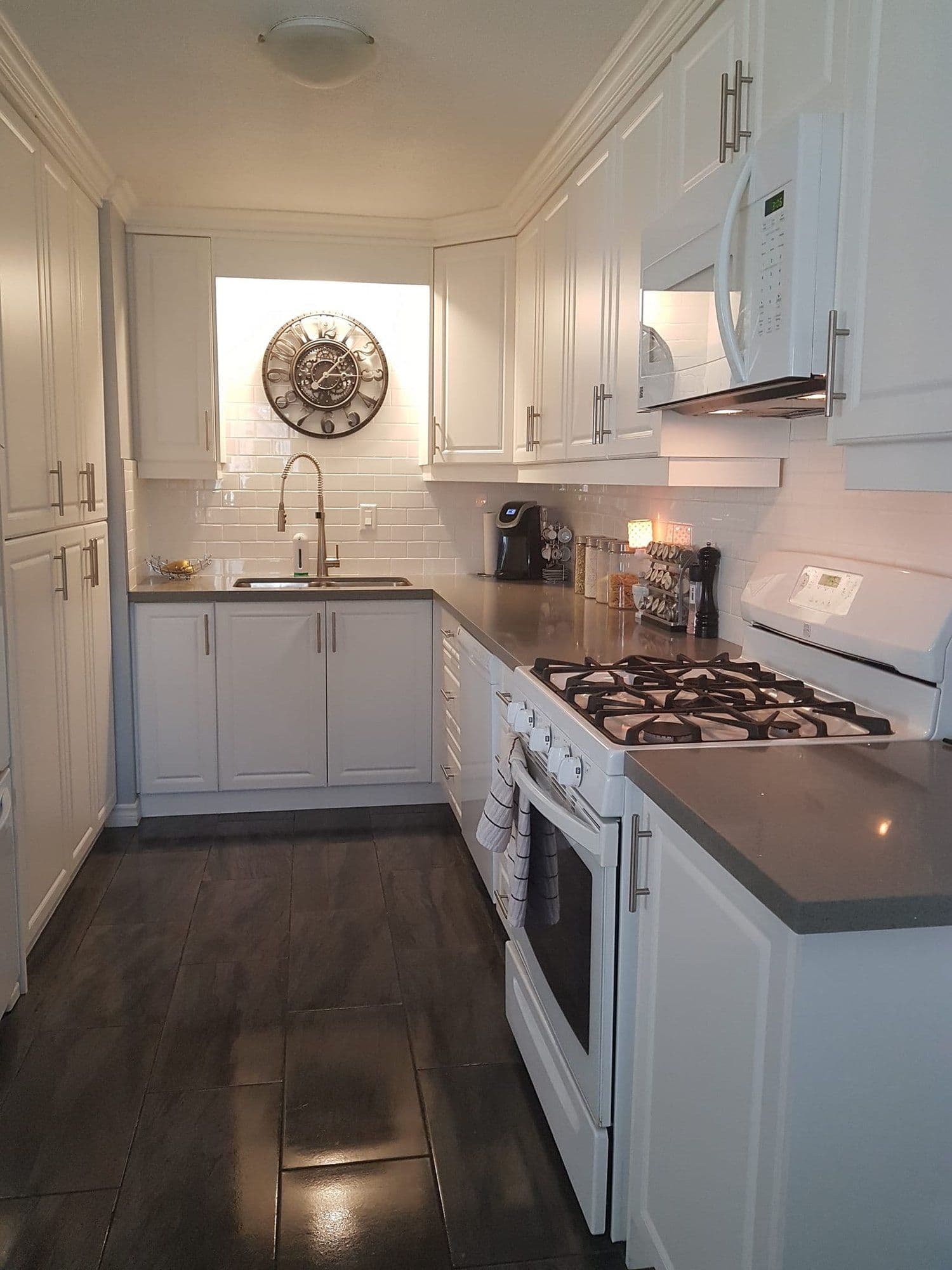 A bright, just-cleaned kitchen with stainless appliances and gleaming white cabinetry